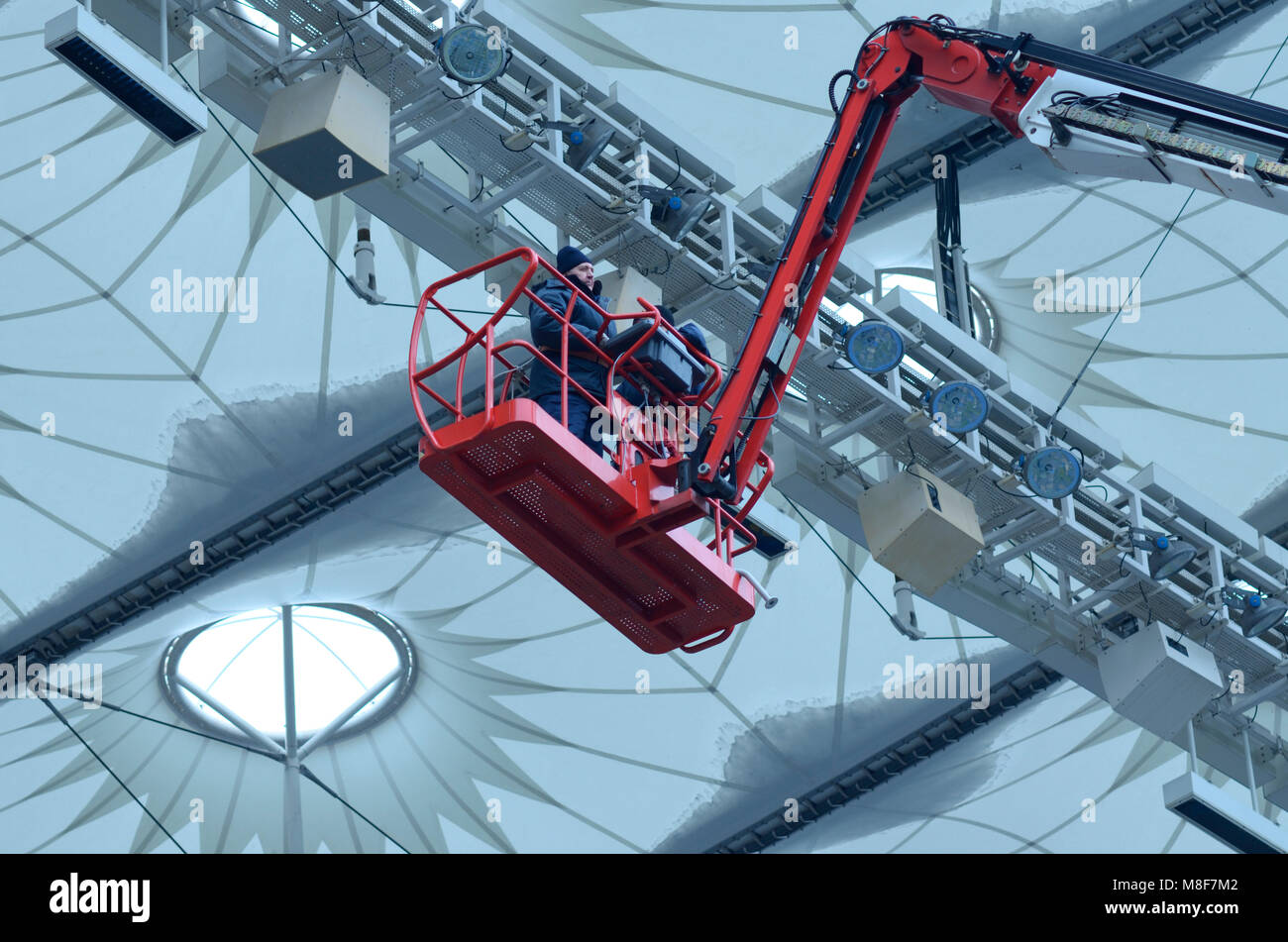 Workers repair sports lighting fixtures of the Olympic National Sports Complex stadium using boom lift. March 16, 2018. Kiev, Ukraine Stock Photo