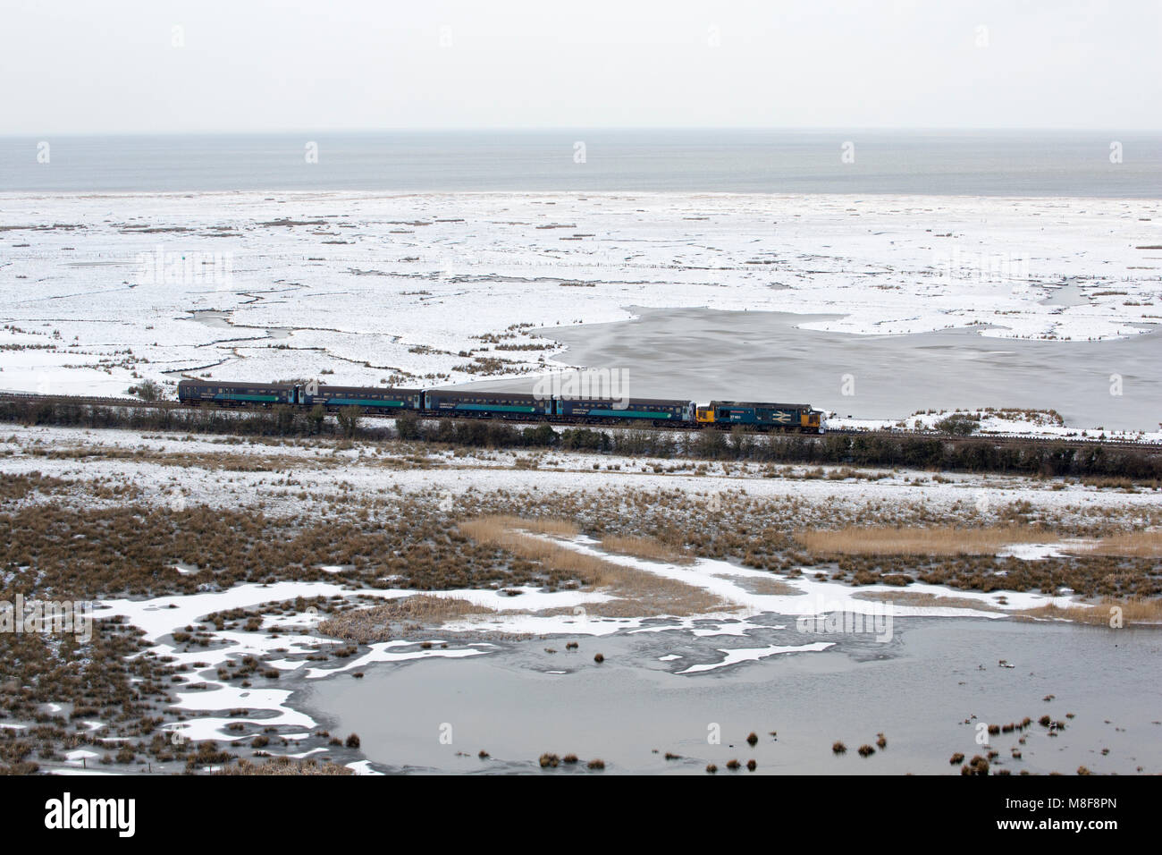 Mary Queen of Scots class 37 diesel-electric locomotive crossing saltmarsh between warton and silverdale, Lancashire UK during the beast from the east Stock Photo