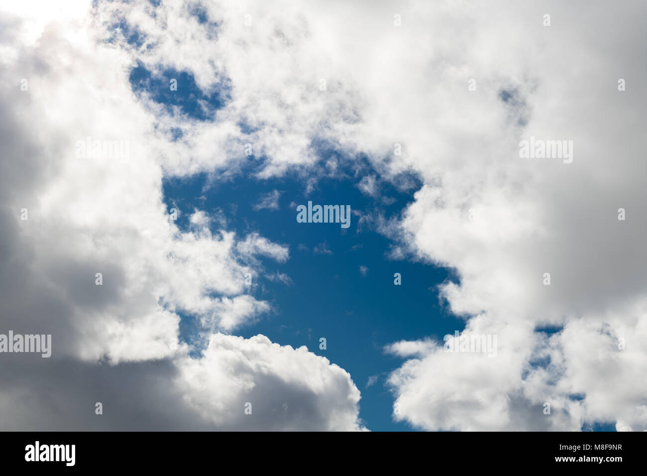 Clouds in the sky that are white with a large patch of blue in the middle Stock Photo
