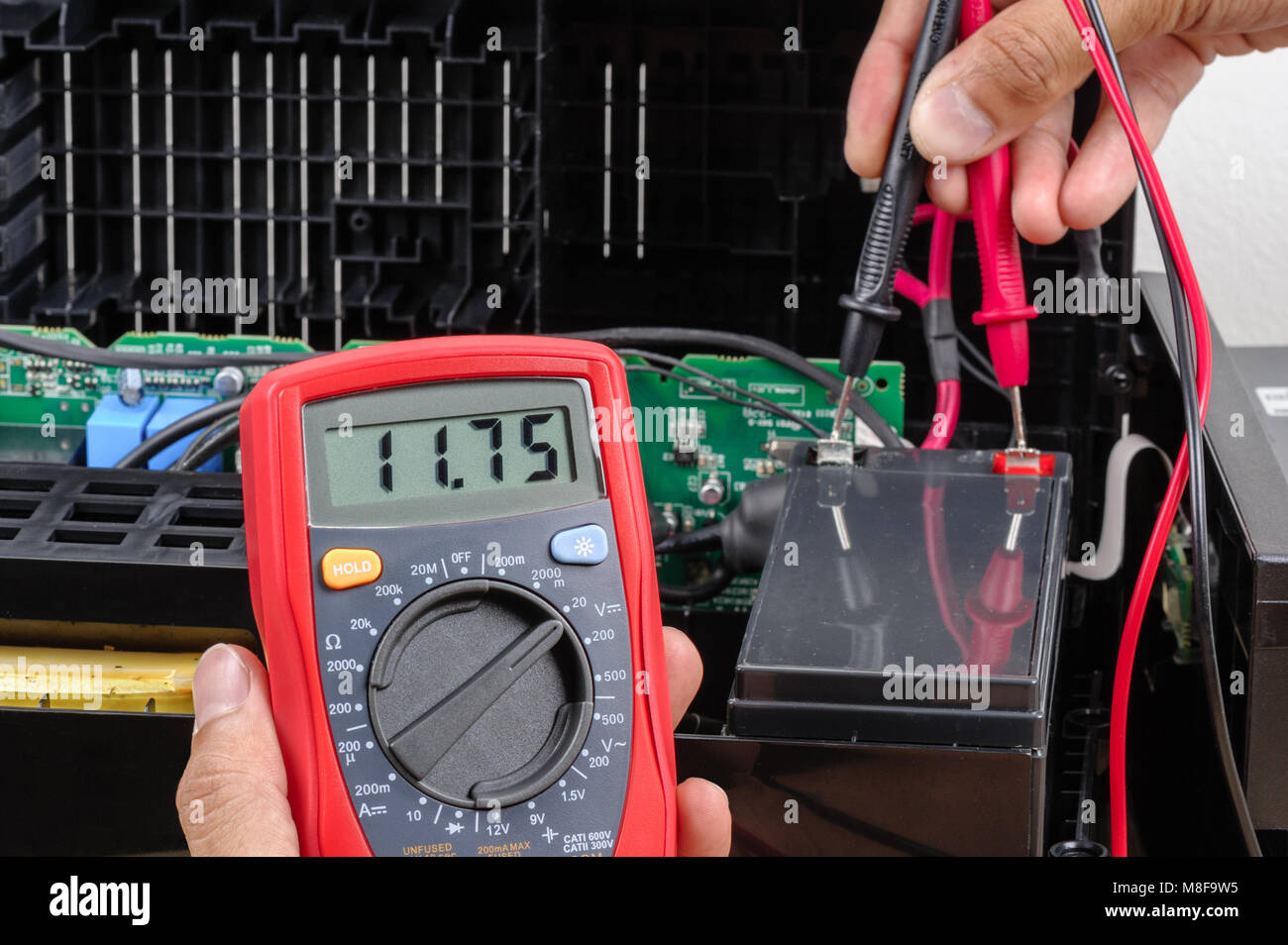 Technician measuring the voltage of battery for UPS (Uninterruptible