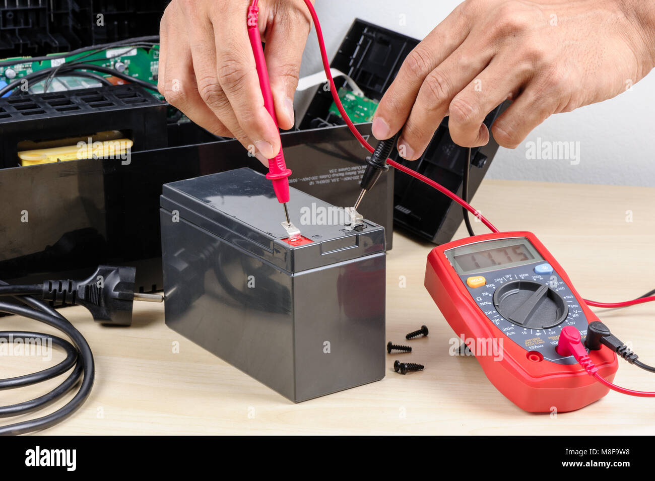 Technician measuring the voltage of battery for UPS (Uninterruptible