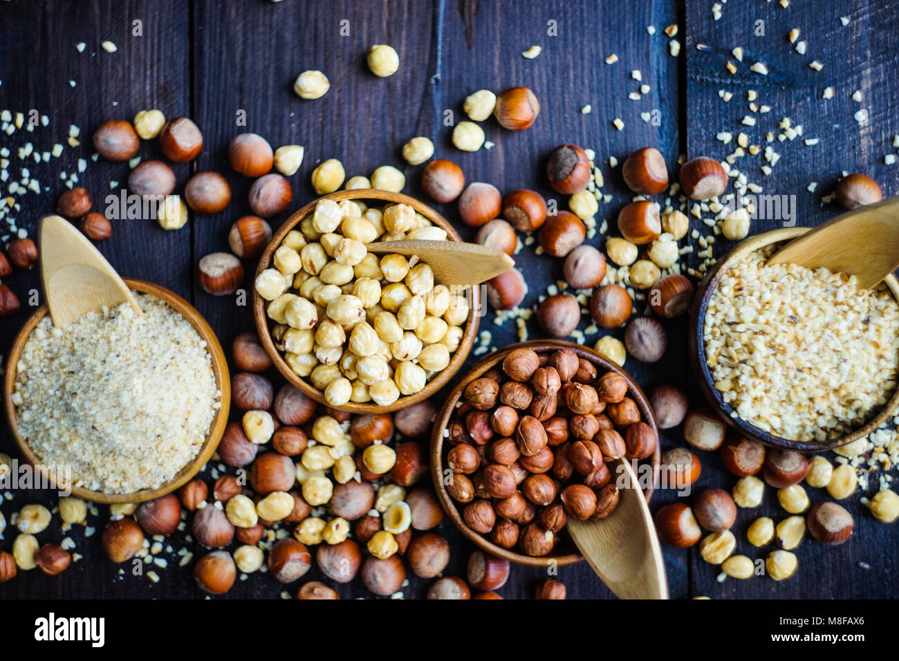 Different types of hazelnuts on dark wooden background with copyspace