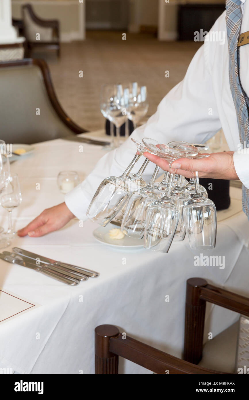 Woman setting wine glasses in place for formal wine club dinner, Naples, Florida, USA Stock Photo