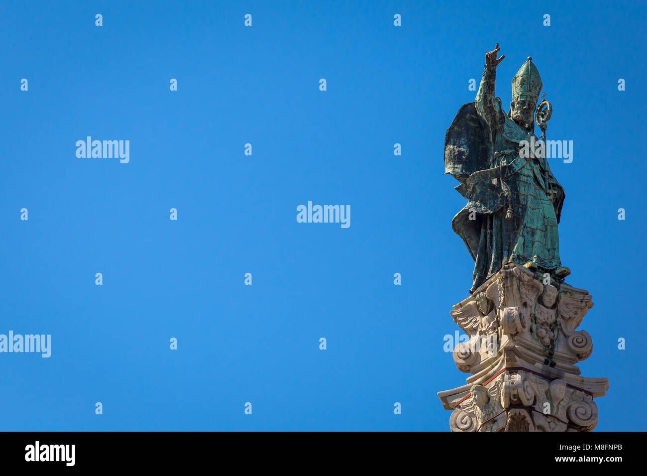 The symbol of Lecce town (Italy): Saint Oronzo (Sant'Oronzo) posed on the column at the center of the main town Square. Blue backgroud with copy space Stock Photo