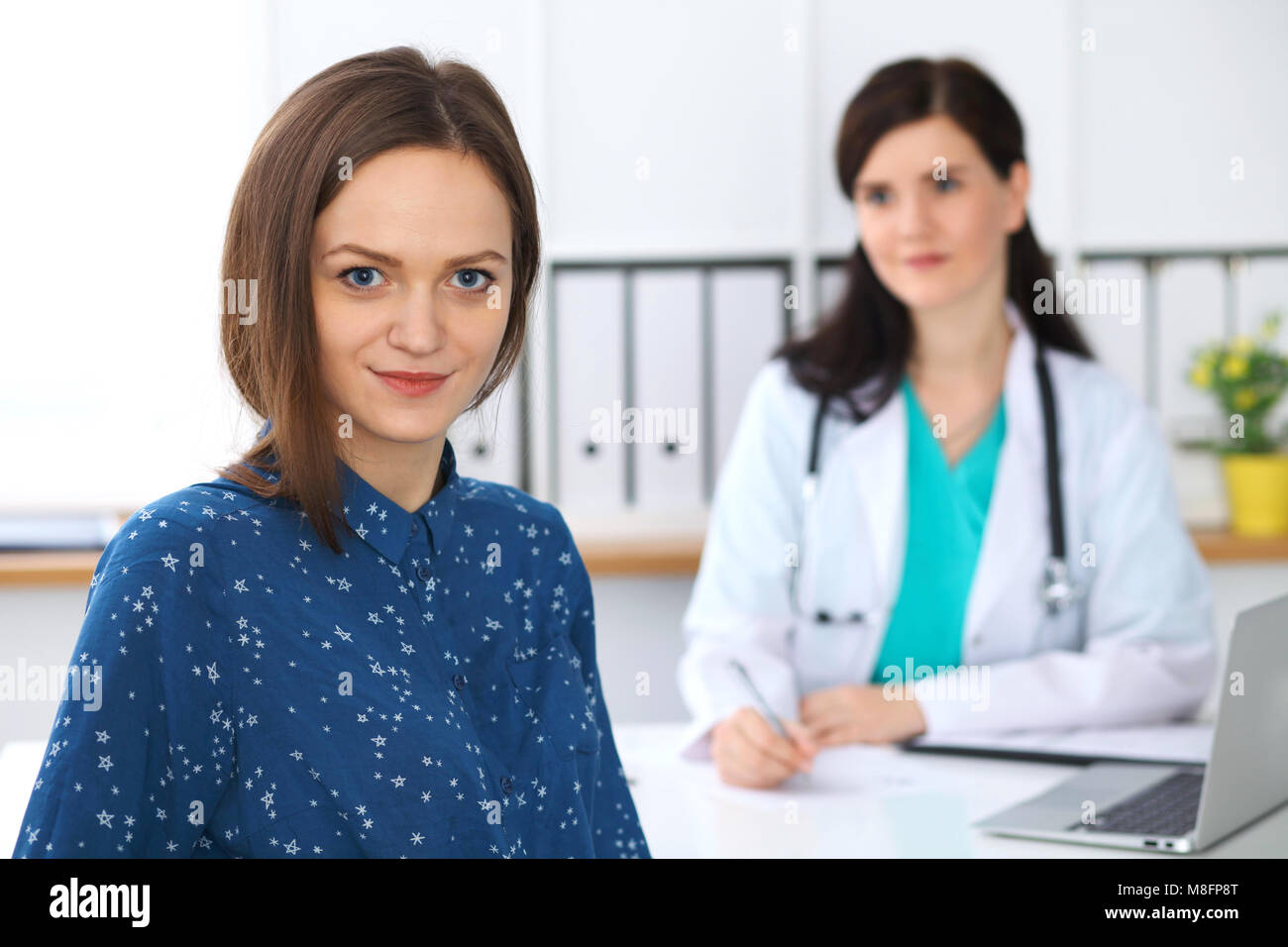 Doctor and patient having a talk while sitting at the desk. Focus on ...
