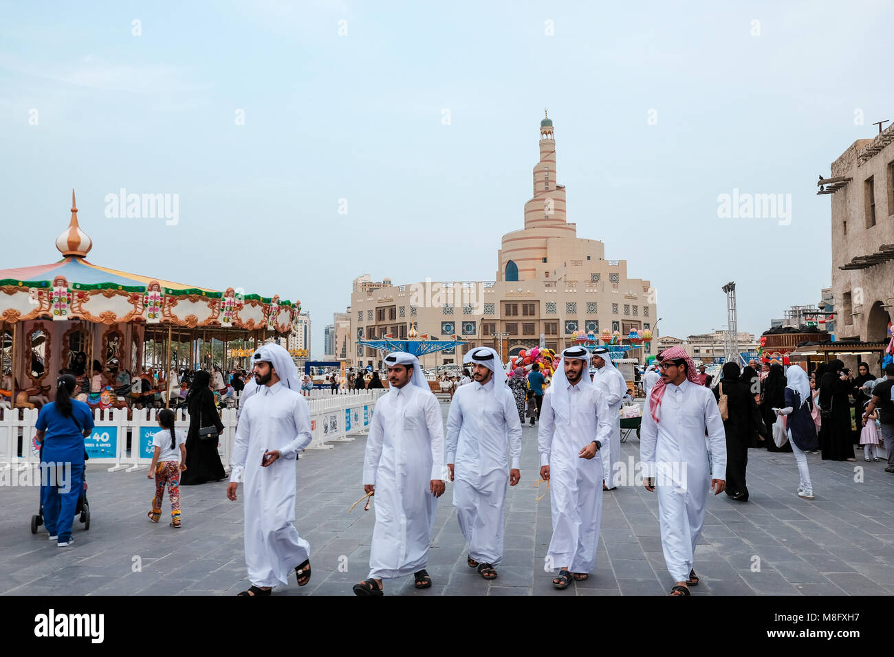 Young Qatari men dressed in traditional thobes walk through Souq Waqif, Doha capital of Qatar Stock Photo