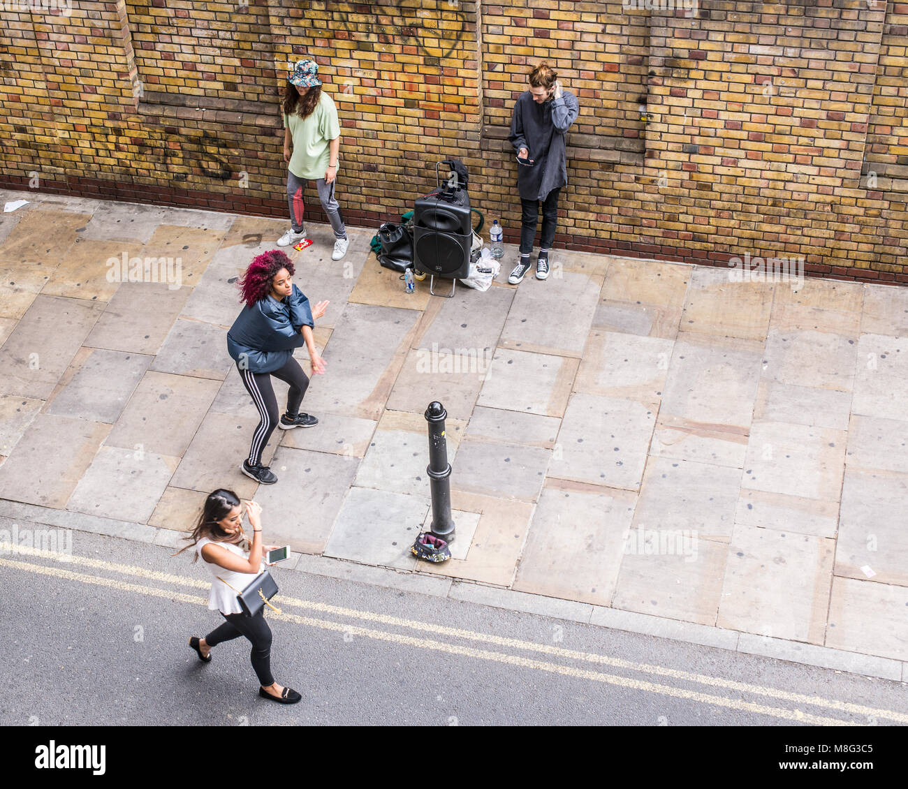Street dance improvised performance by hip-hop acrobatic dancers and people watching outside The Old Truman Brewery, Ely's Yard, Shoreditch, London, U Stock Photo