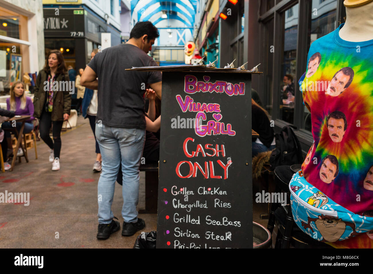 People shopping in the indoor Brixton Village Market, a multicultural community market with independent shops and ethnic restaurants in South London. Stock Photo