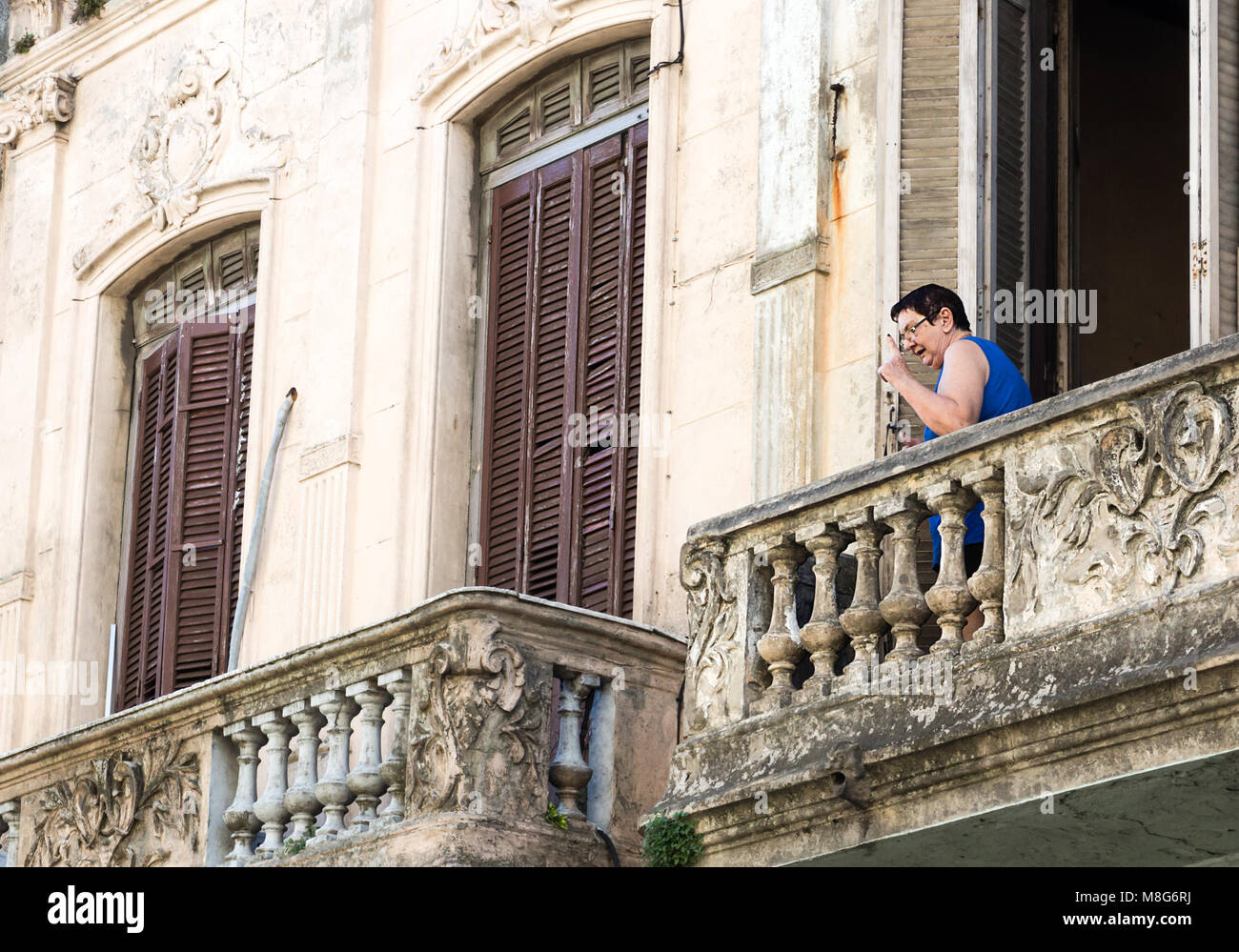 Montevideo, Uruguay - February 25th, 2018: A senior woman pointing up from the balcony of her home at the downtown of Montevideo, Uruguay. Stock Photo