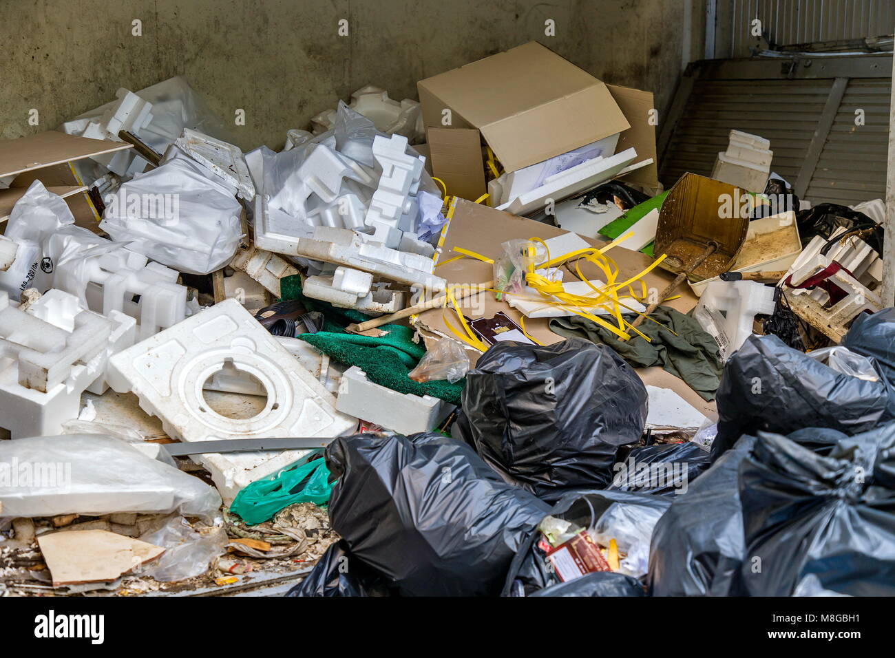 Waste bin with foam, paper crate, black garbage bag, old shoes, broken