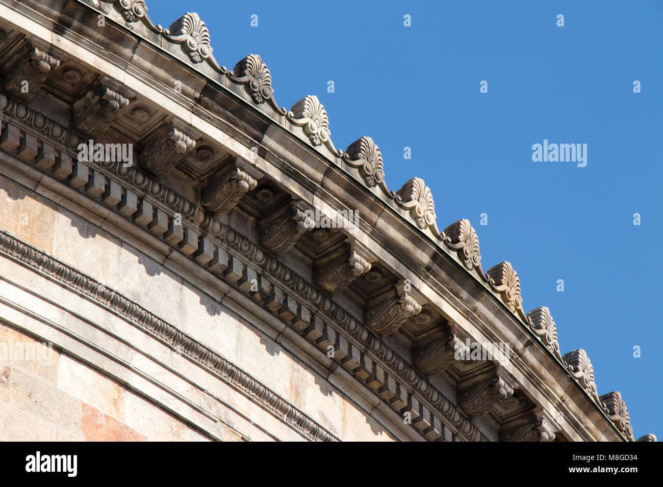 Detail of a neoclassical building with round cornice ornaments against a blue sky Stock Photo
