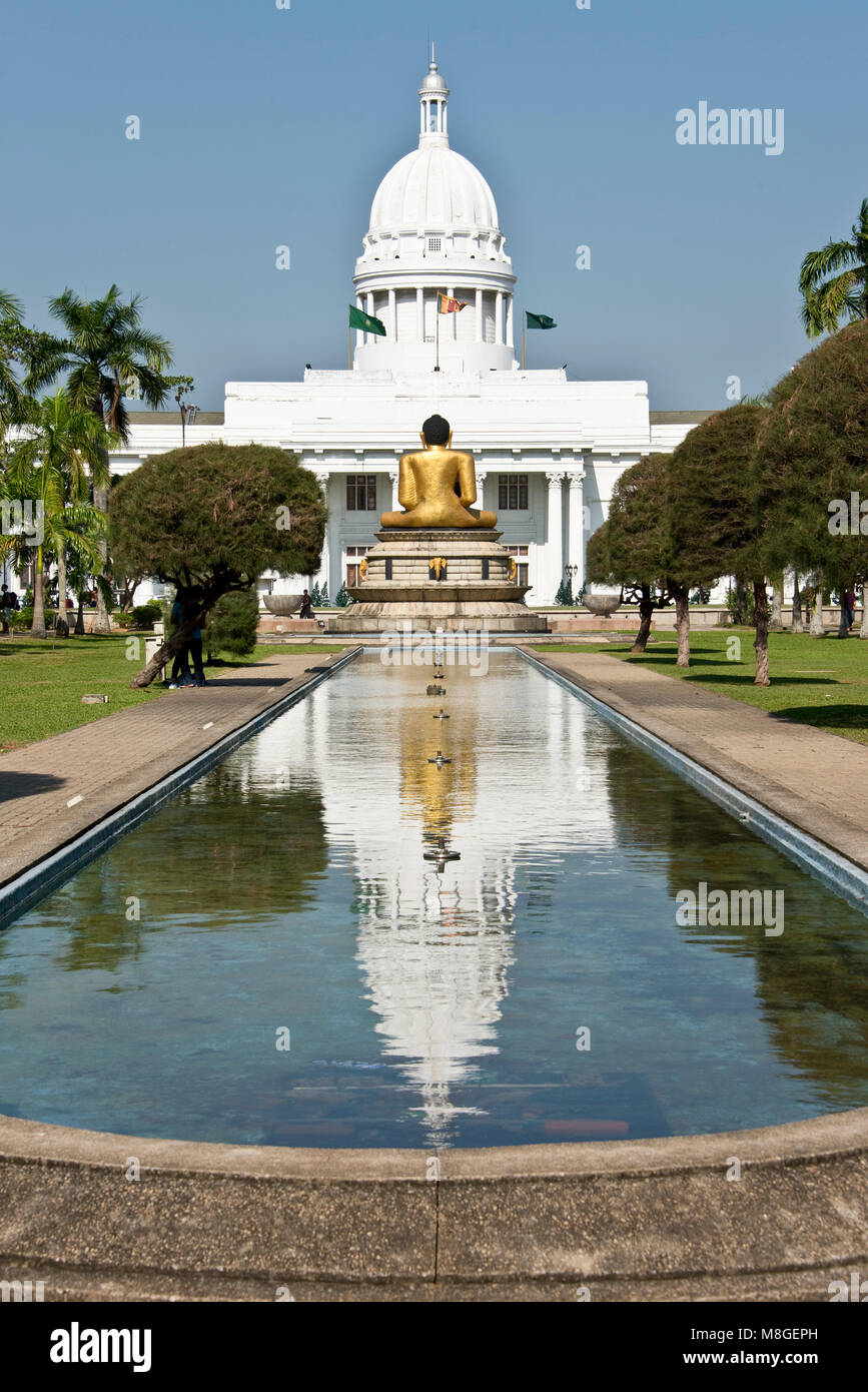 The Town Hall Colombo aka Columbo Town Hall reflected in the water pool inside Viharamahadevi Park with the golden Buddha statue in front. Stock Photo