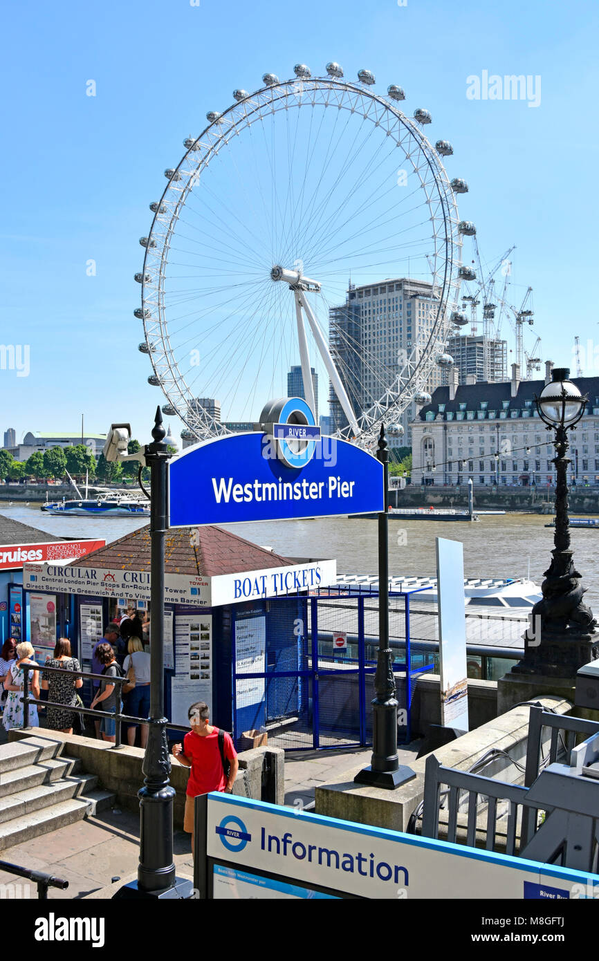 Tourists buying River Thames tour boat tickets at Transport for London Westminster pier for  sightseeing excursions with iconic London Eye beyond UK Stock Photo