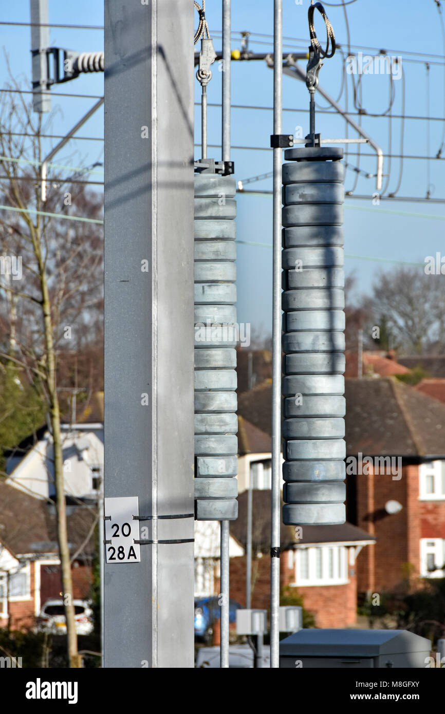 Heavy disc weights placed on long rod to correctly tension electricity overhead cables that supply electric current to trains on many UK railway lines Stock Photo