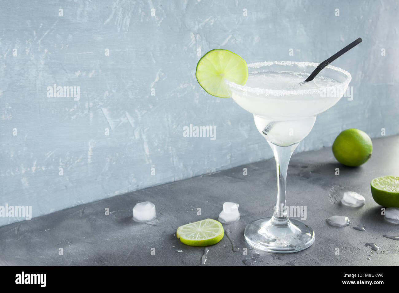Margarita Сocktail with lime and ice on grey concrete background, copy space. Classic Margarita or Daiquiry Cocktail. Stock Photo