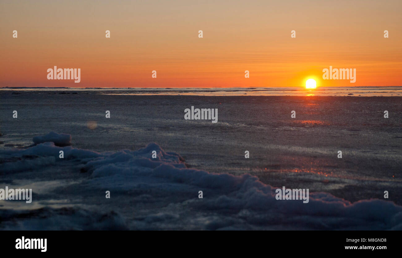 Bering Sea Sunrise   .Good morning, Alaska! The waves are silenced to a whisper as they congeal into a frozen substance. By the winter solstice, the sun will remain low on the horizon, rising and setting in less than 4 hours. Stock Photo