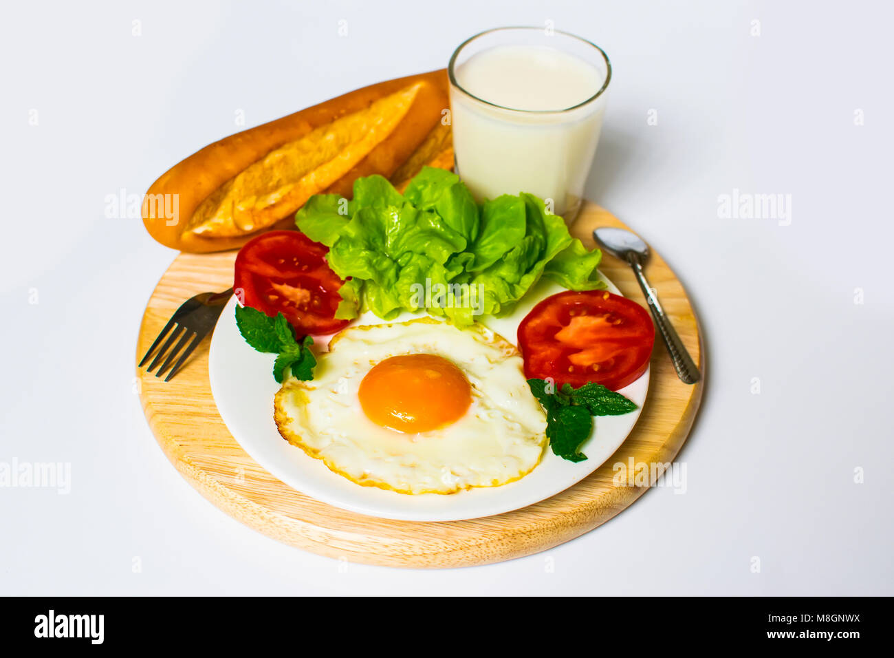 Breakfast with bread, fried eggs, milk and vegetables and fried tomato