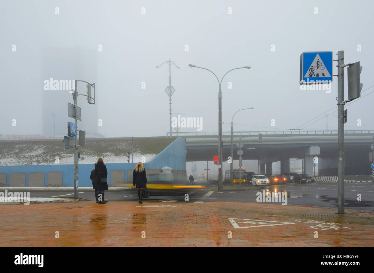 Minsk, Belarus- March 14, 2018: Road junction on Independence Avenue near Alexandrov Passage business center in thick fog. People stand near crossroad Stock Photo