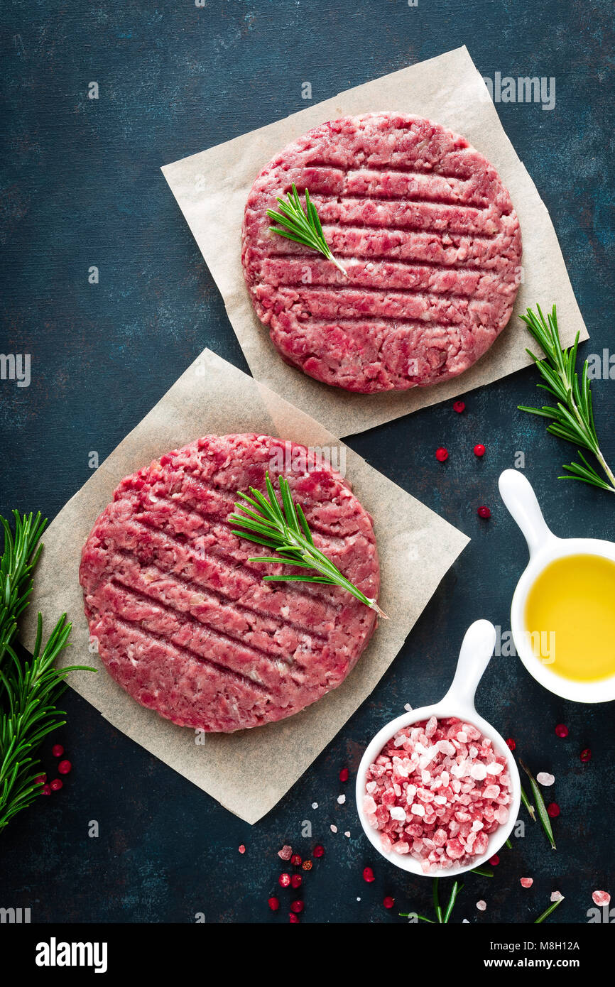 Fresh minced beef meat burgers with spices on dark background. Raw