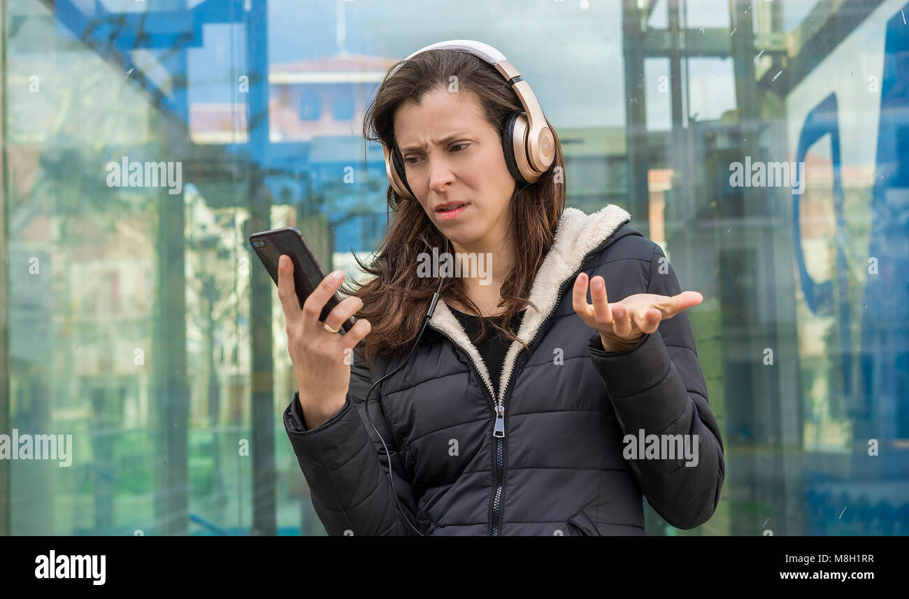 Relation, jealousy and suspicion in the cell phone, couple problems, adult woman looking at suspicious messages on the phone while on the street liste Stock Photo