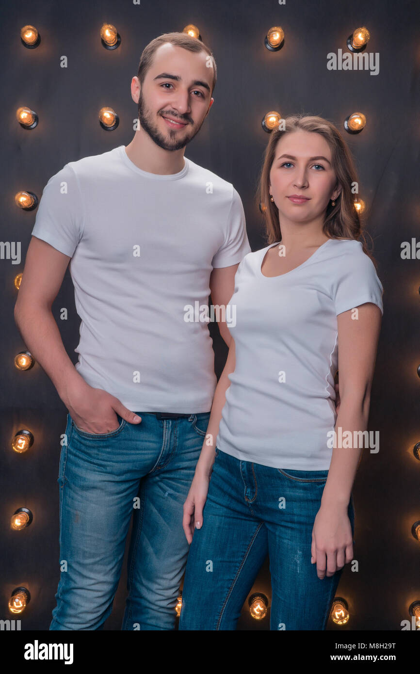 A girl and a boy model posing in white shirts and blue jeans in the studio Stock Photo