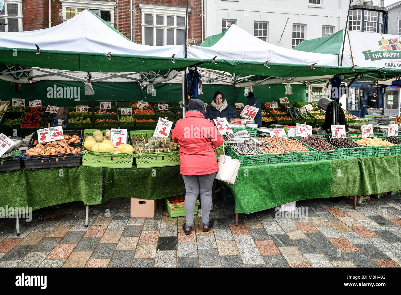 A customer buys fruit and veg at Salisbury outdoor market in the snow, as the investigation into the suspected nerve agent attack on Russian double agent Sergei Skripal and his daughter Yulia continues. Stock Photo