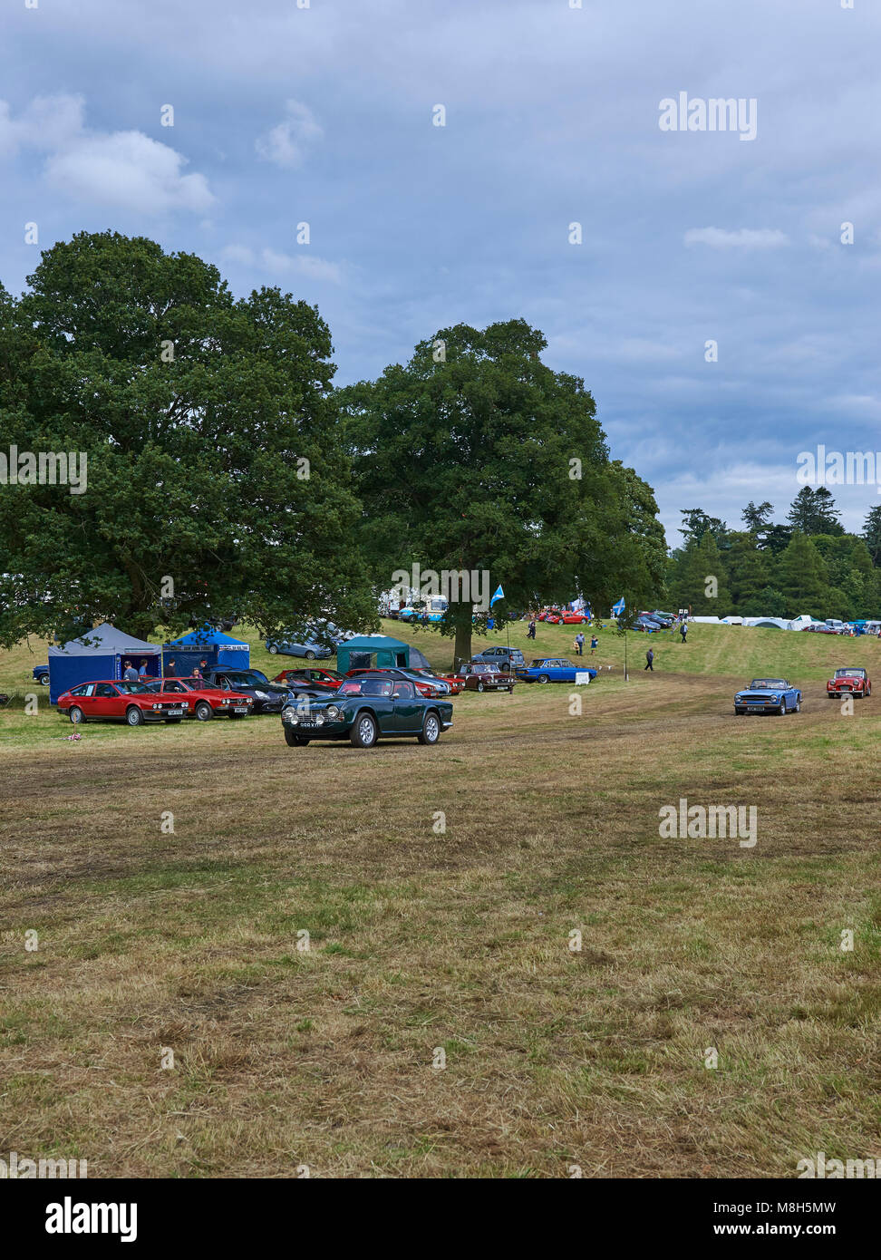 Three Vintage Triumph Cars being driven across the Show Field at the Strathmore Vintage Vehicle Show, held in the grounds of Glamis Castle, Perthshire Stock Photo