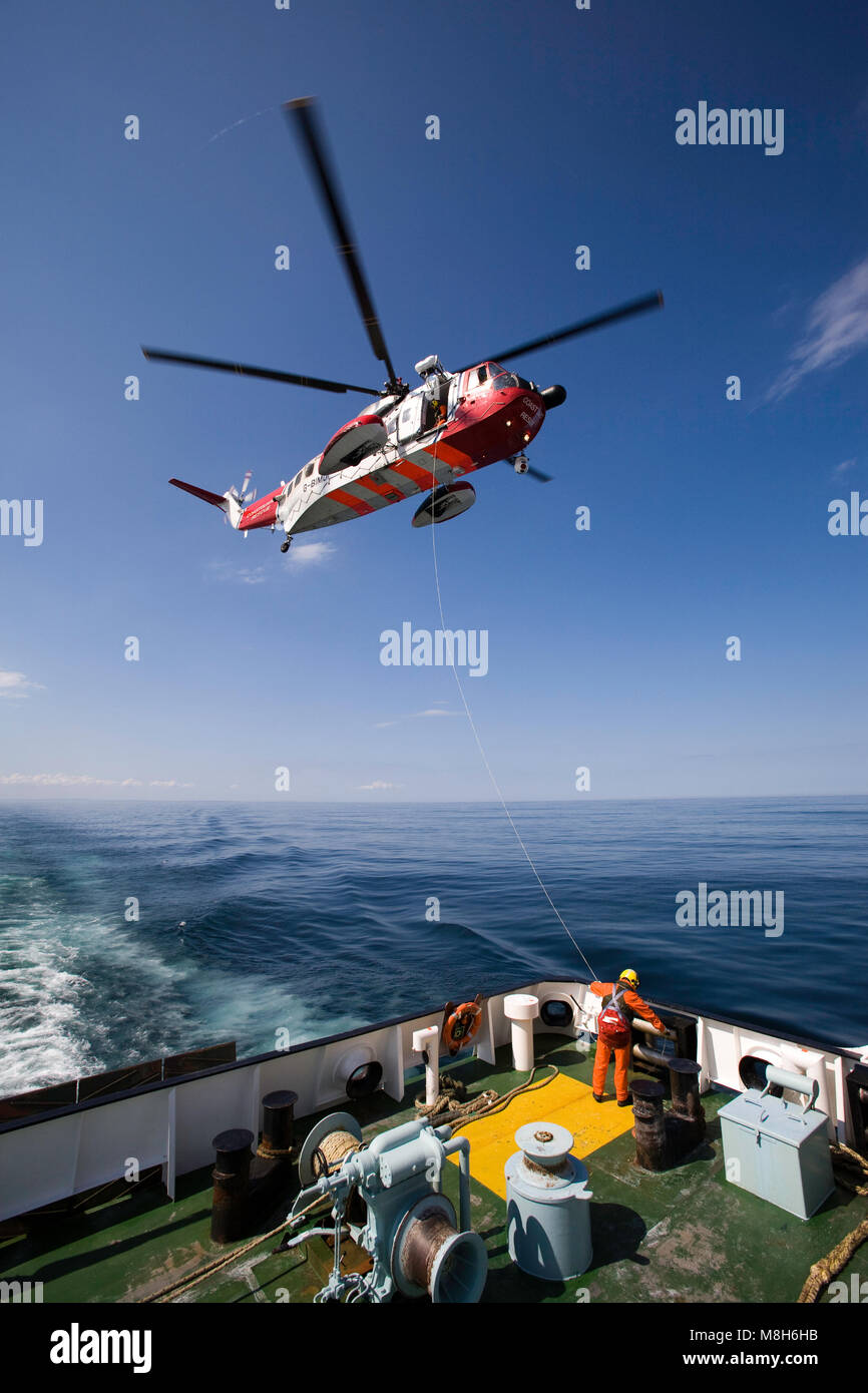 HM Coastguard Sikorsky helicopter carries out a training rescue in the Minch over the Caledonian Macbrayne Ulapool to Stornoway ferry. Stock Photo