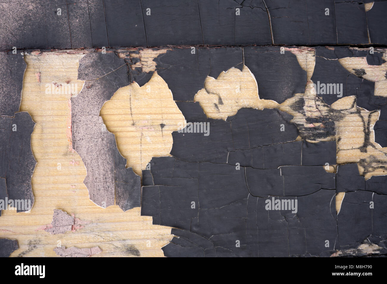 Cracking and peeling black paint on a wall. Vintage wood background