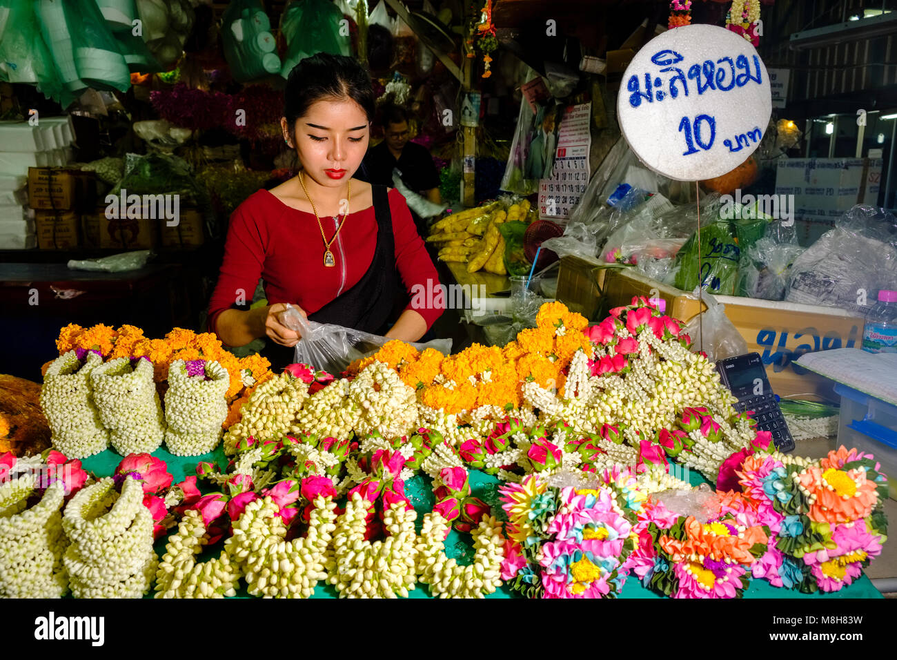 A young woman is arranging flowers and blossoms at the 24 hours flower market Stock Photo