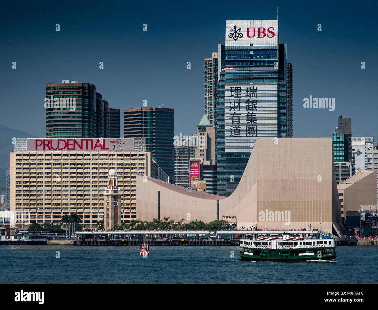 Hong Kong - Star Ferry sails in front of large UBS and Prudential adverts on the Kowloon side of Victoria Harbour Stock Photo