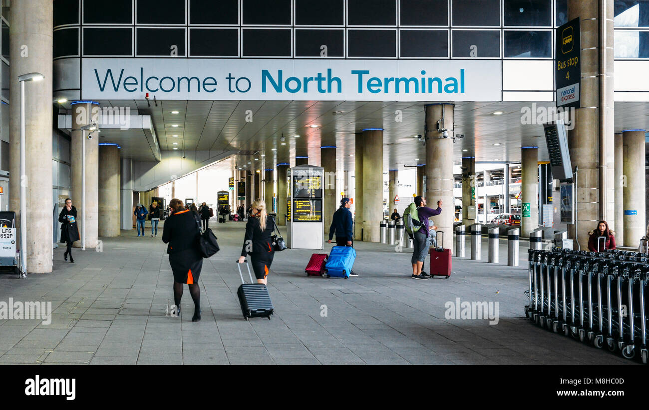 Sign welcoming passengers to London Gatwick's North Terminal servicing destinations in Europe and beyond. Passengers and air crew on foreground Stock Photo