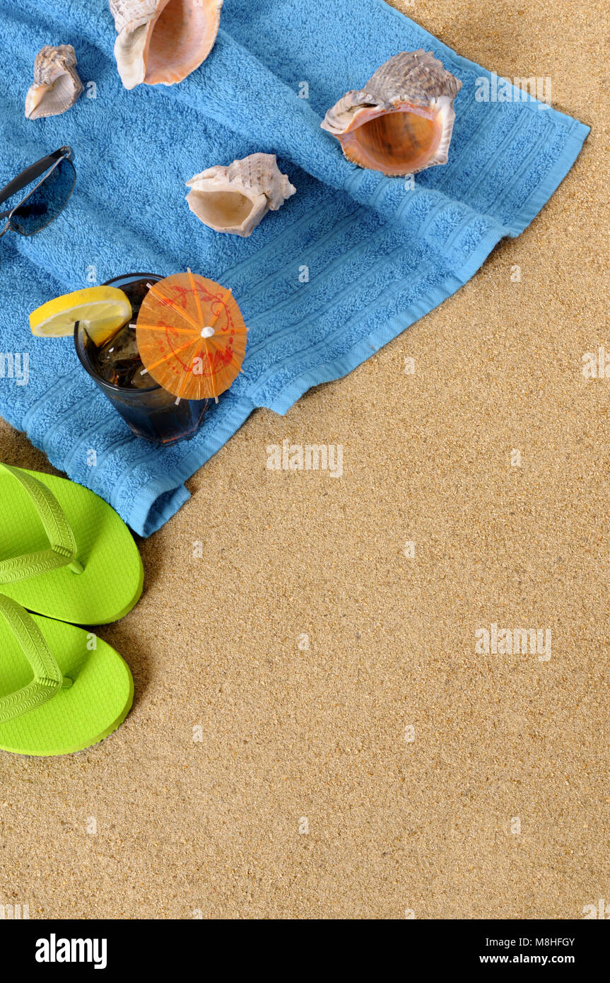 Beach background with towel, glass of iced cola and flip flops. Space