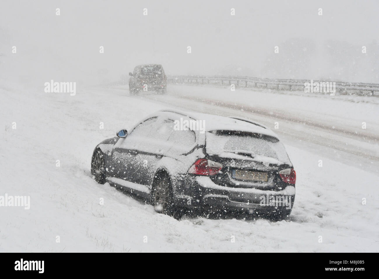 Long Bredy, Dorset, UK.  18th March 2018.  UK Weather.  An abandoned car in the blizzard Conditions on the A35 at Long Bredy between Bridport and Dorchester in Dorset as heavy snow which has covered the road, makes driving hazardous.  Picture Credit: Graham Hunt/Alamy Live News. Stock Photo