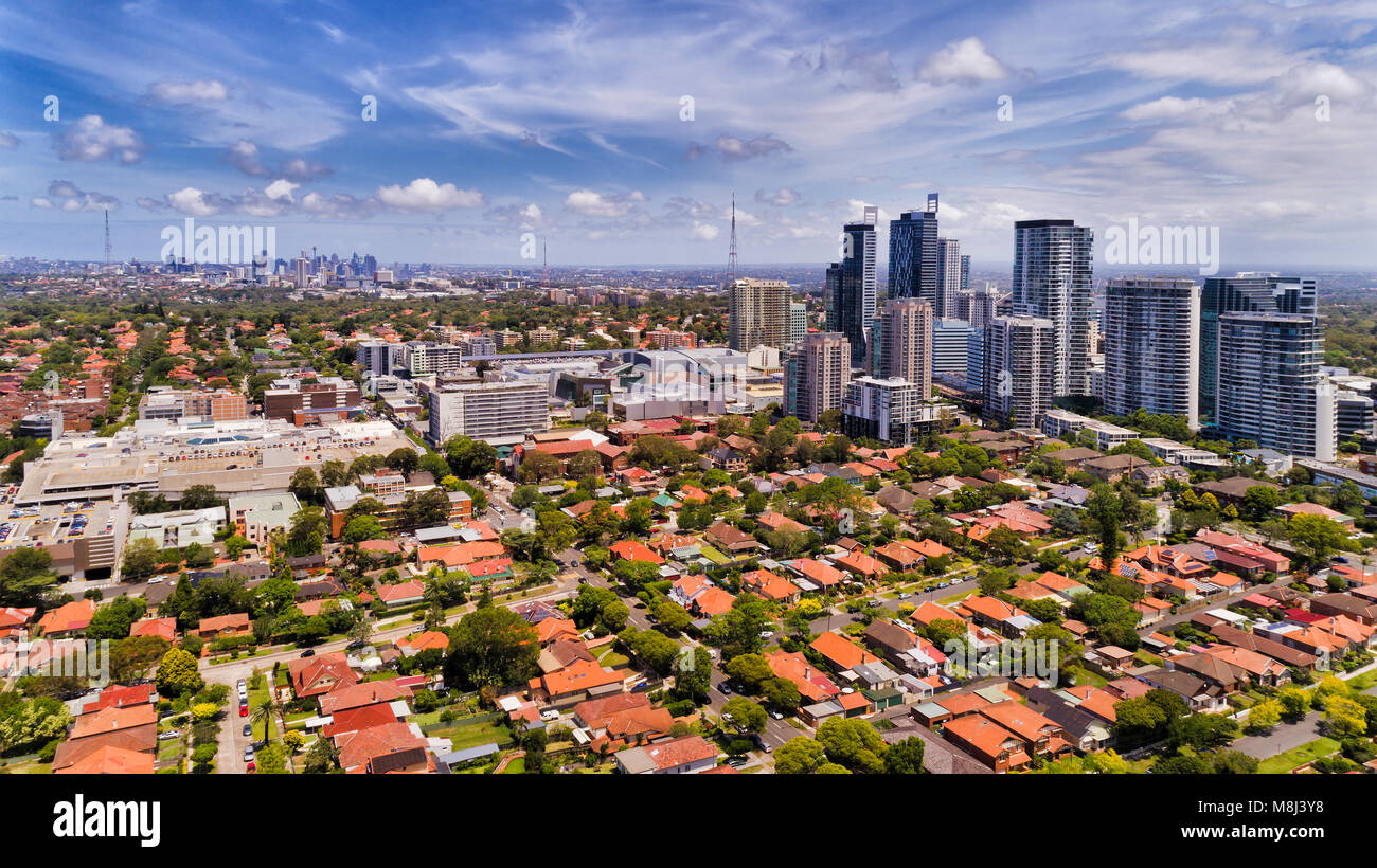 Modern urban high-rise towers of Chatswood suburb in Sydney surrounded by residential low houses with red roofs and local streets in view of distant c Stock Photo