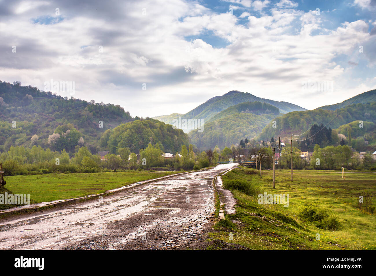 Mountain countryside. Road and village in green mountain valley. Spring ...