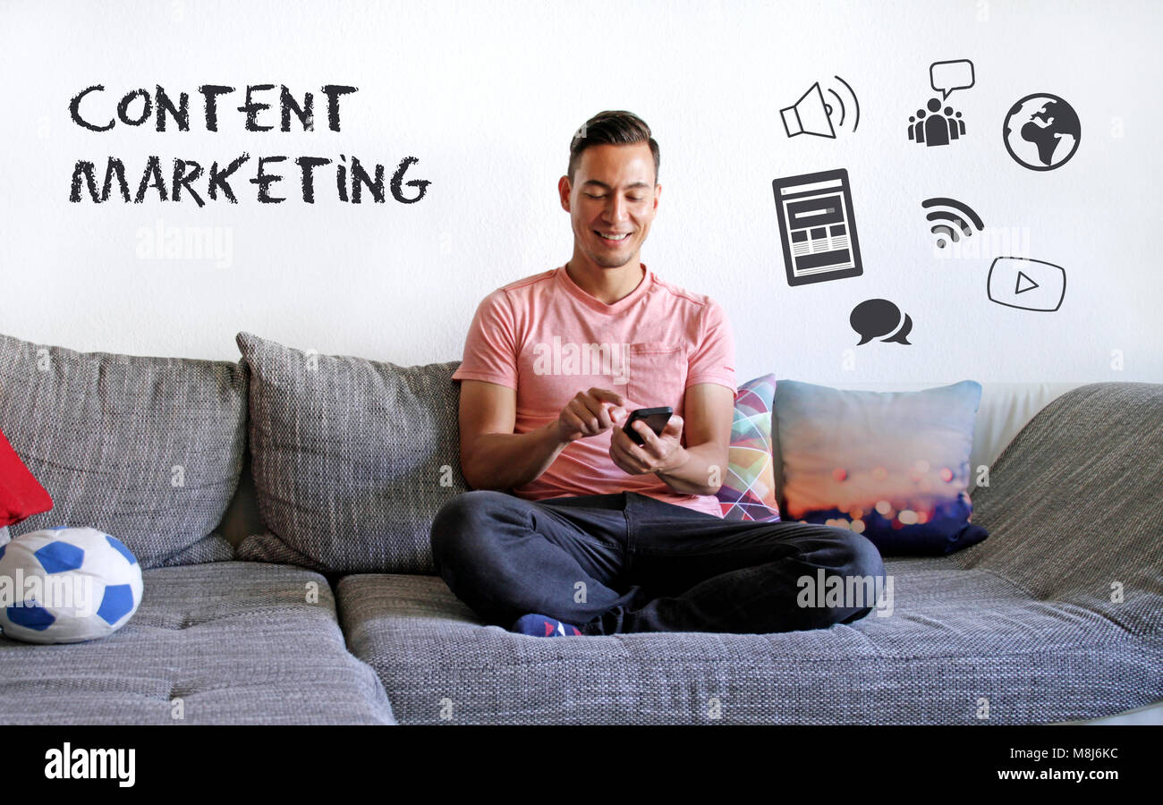Content Marketing: Smiling man on couch interacting with digital content Stock Photo