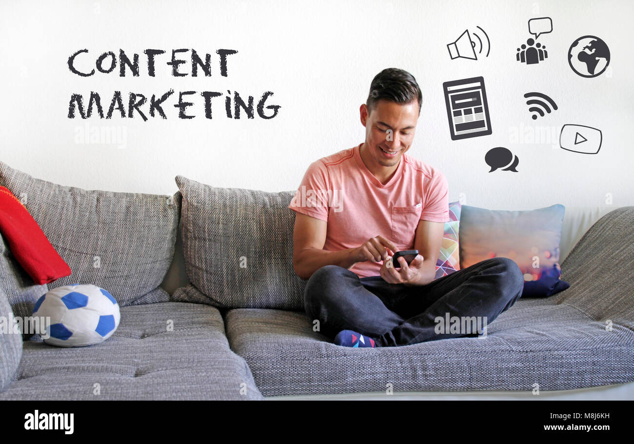 Content Marketing: Smiling man on couch interacting with digital content Stock Photo