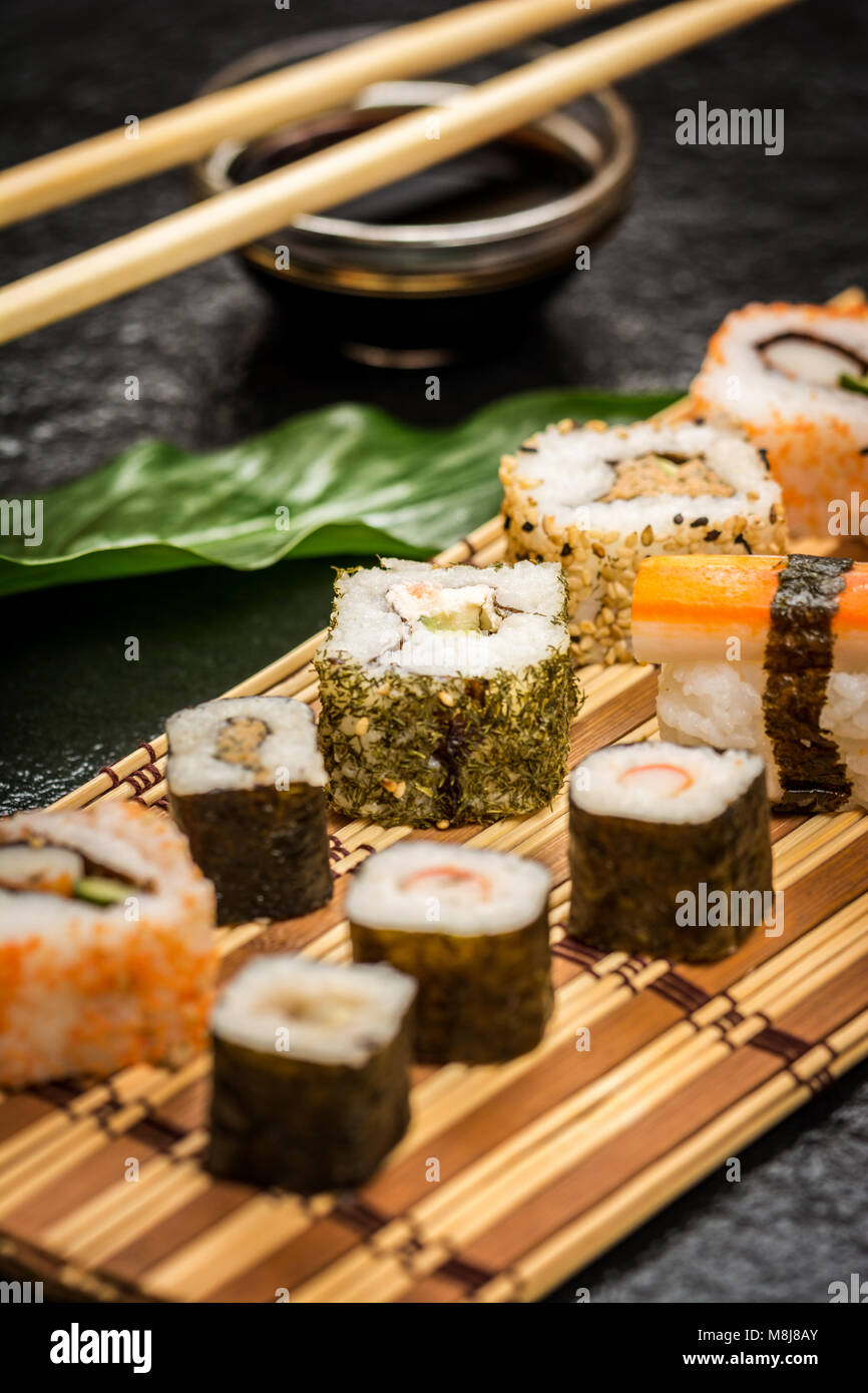 Traditional japanese sushi rolls hosomaki,uramaki, nigiri  and chopsticks and soy sauce on stone desk Stock Photo