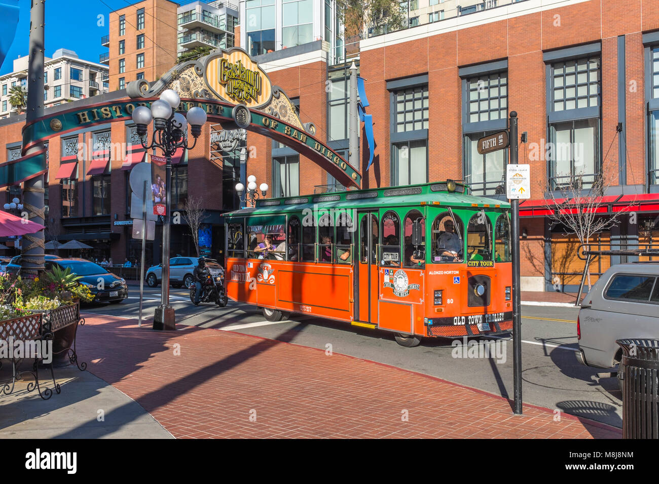 SAN DIEGO, CALIFORNIA, USA - Green and Orange Old Town Trolley city tour vehicle passing under the entrance arch to the historic Gaslamp Quarter. Stock Photo