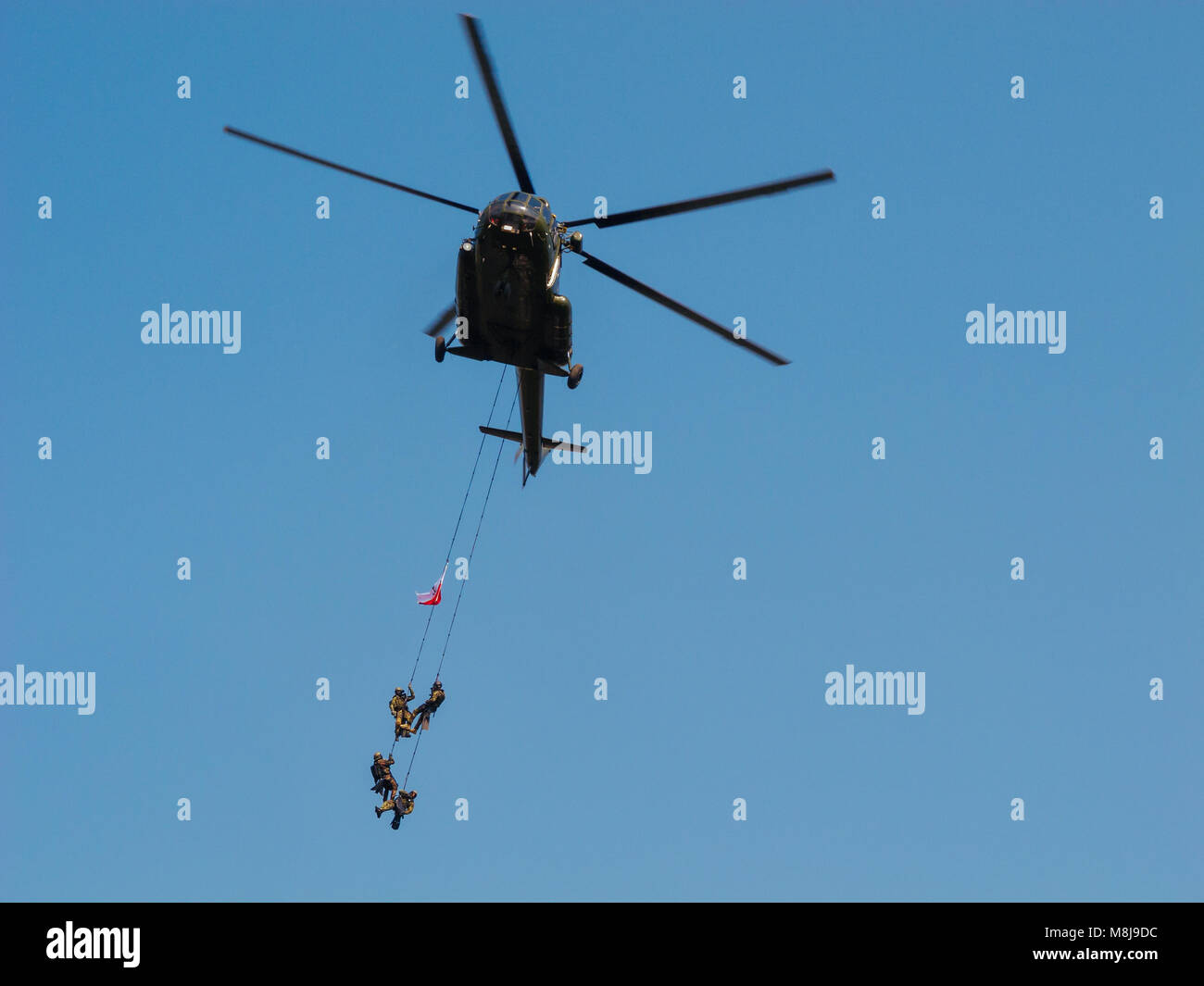 WARSAW, POLAND - SEPTEMBER 13, 2014: Polish GROM Special Forces show off their skills hanging on ropes from a helicopter. Stock Photo