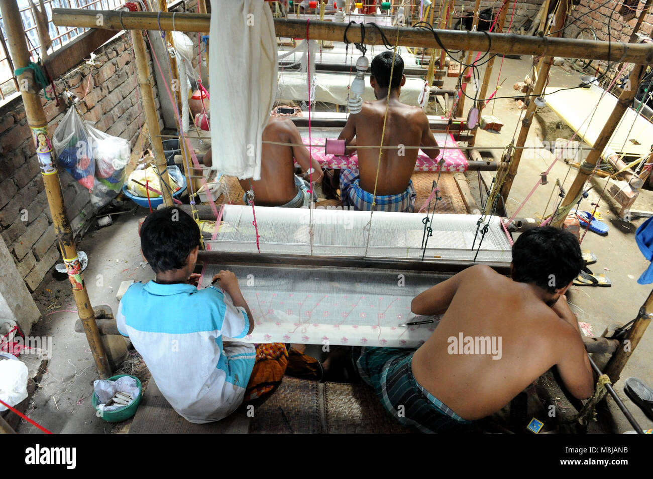 NARAYANGANJ, BANGLADESH - AUGUST 24, 2016: Handloom weaver weaves Jamdani saree on a traditional wooden hand weaving loom at Rupganj in Narayanganj, B Stock Photo