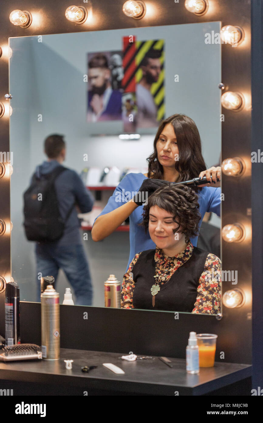 KIEV, UKRAINE OCTOBER 08, 2017 Hairdresser makes hairstyle on