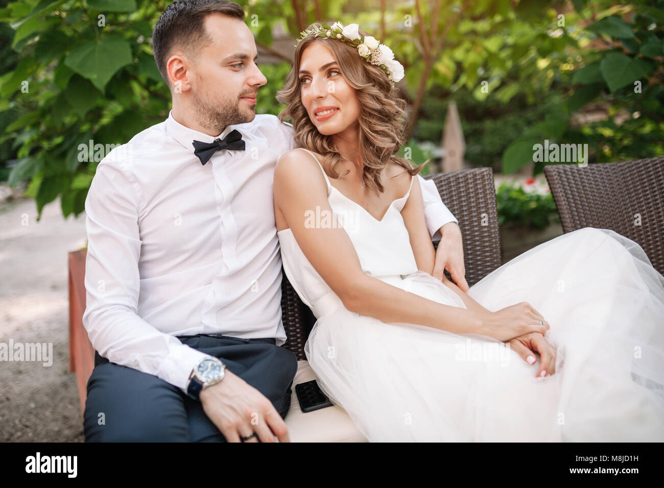 the bride and groom sitting on a chair with arms around each other ...