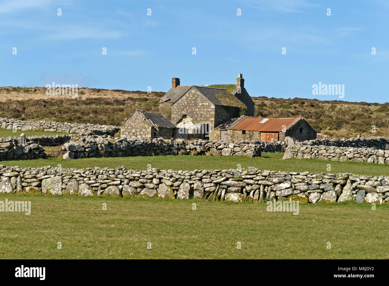 Old deserted Cornish stone farmhouse buildings, green fields and dry-stone walls, Cornwall, England, UK Stock Photo