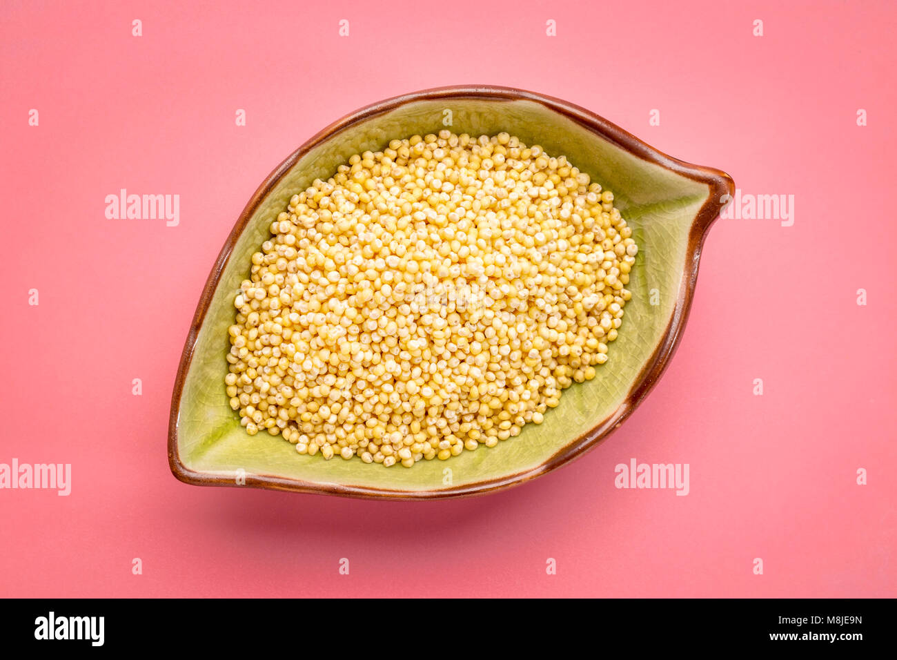 gluten free hulled millet grain in a ceramic leaf shpaed bowl against