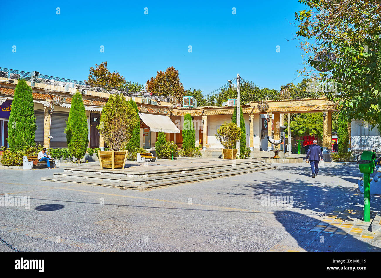 ISFAHAN, IRAN - OCTOBER 20,2017: The tiny park with thuja trees in Julfa square of Armenian neighborhood, this area is surrounded by stores and cafes, Stock Photo