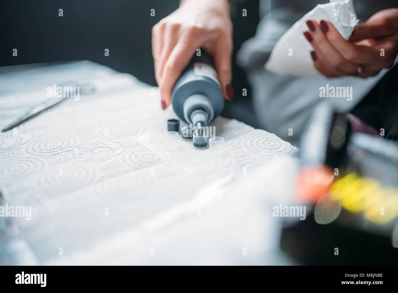 Female tattooist hands in blue sterile gloves holds tattoo machine