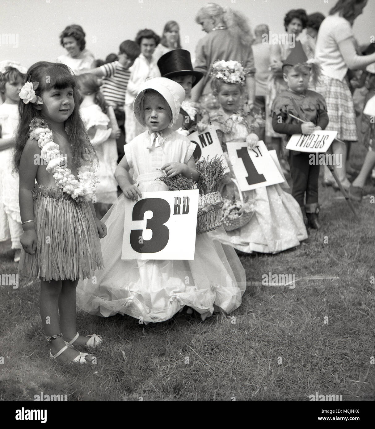 1950s, historical, young children taking part in a fancy dress competition at an outdoor fete, stand together holding their placings after the judging, England, UK. Stock Photo