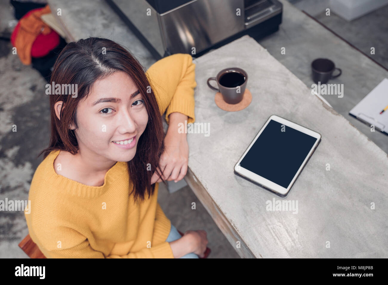 Asian woman using tablet on cafe counter bar with coffee cup and smile emotion,leisure lifestyle concept Stock Photo